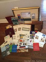 Wide view showing the assortment of stamp albums, framed piece, souvenir collections, first day covers, and postal booklets spread on floor.