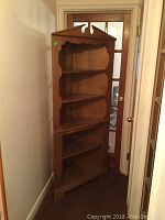 Full side view of the wooden corner cupboard showing its depth and shape.