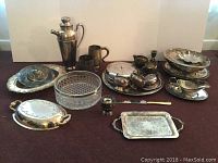 Wide view of all items in the lot showing arrangement of silver plate serving pieces and glass bowl.