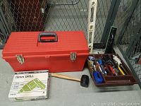 Full view of red toolbox, Black & Decker drill box, rubber mallet, and organizer tray with tools next to toolbox.