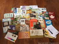 Complete view of the assortment of stamps, catalogs, booklets, and first day covers laid out on a surface.