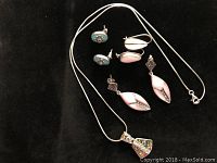 The entire lot showing four pairs of earrings and one necklace on a black fabric background