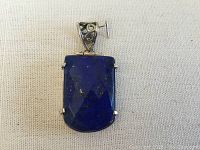 Front view of the rectangular faceted lapis lazuli stone pendant with sterling silver prong setting and decorative bail.