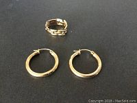 Pair of polished 14K gold hoop earrings and 10K gold chain link ring on black background
