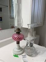 Both oil lamps side by side showing size difference, glass fonts, burners and chimneys