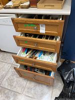 Four kitchen drawers partially open showing assortment of utensils and cutlery