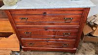 Front view of oak dresser showing four drawers, marble top, brass handles