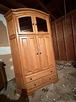 Front view of light oak corner entertainment center showing glass doors, panel doors and drawers