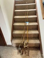 Three rod-and-reel combos on staircase showing full lengths and overall wear