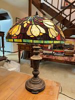 Full view of lamp on table showing stained glass shade and metal base