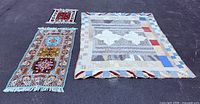 Group shot of area rug, prayer mat and quilt on ground