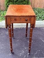 Three-quarter view showing table top, drawer, legs, casters
