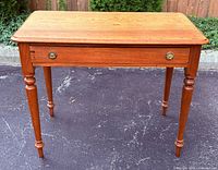 Front view of wooden table showing top, legs and drawer