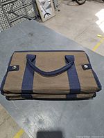 Organizer folded flat showing brown exterior with navy trim and handles