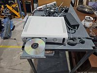 Console with disc tray open, controllers, power brick, cables visible