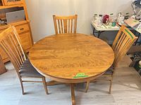 Round honey oak dining table with three of six chairs visible