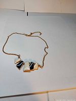 Full view of gold-tone chain necklace with geometric enamel pendants