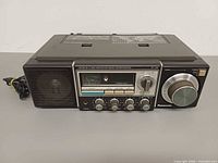 Front angled view showing speaker, dial, knobs and attached power cord