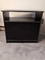 Full view of black MDF TV stand showing open shelf and cabinet doors
