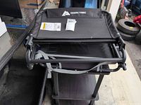 Folded Ozark Trail stadium seat showing brand tag, metal frame, carry strap