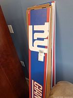 Full-length view of sign within cardboard sleeve showing team graphics
