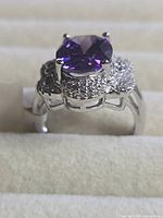 Side view of silver-tone ring showing large purple centre stone and pavé clear stones