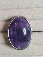 Front view of ring showing full oval purple cabochon stone set in silver-tone bezel