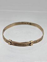 Full view of oval bangle showing engraving and slider sleeves