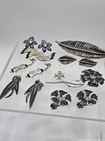 All thirteen jewelry pieces laid out on clear riser