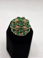Top view of domed cluster ring showing green cabochons and gold floral details