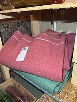 Stacked rose and teal wool blankets on shelf
