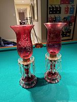 Pair of cranberry etched glass lustres on green surface