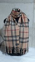 Full view of scarf draped on mannequin showing plaid pattern and fringe