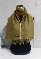 Front view of MGNTI scarf on mannequin showing olive side and fringe
