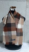 Scarf displayed on mannequin showing plaid pattern and fringe