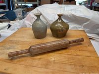 Front view of both vases and rolling pin on wooden surface