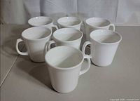 Seven white Corning mugs front and top view