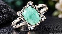 Front angled view of silver ring with oval dyed emerald and four accent stones
