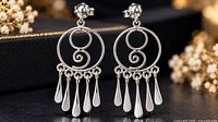 Front view of earrings showing spiral design and droplet dangles