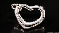 Front view of open heart silver pendant on black background