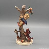 Front view of figurine showing boy, tree, dog, apples