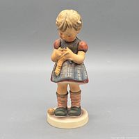 Front view of figurine showing girl sewing and color details