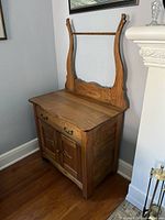 Front angled view of elm wash stand showing drawer, doors, hardware, and shaped backsplash supports