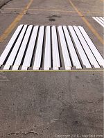 24 white primed MDF step baseboard moulding pieces laid out on pavement, showing length and quantity.