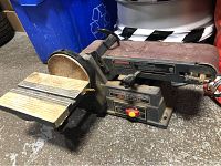 Photo showing side view of the belt and disc sander with wooden support table and sanding belt visible.