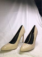 Side view of the beige patent leather high heel pumps showing pointed toe and slim heels.