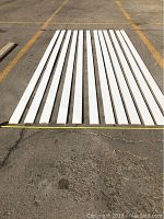 12 white primed MDF baseboard pieces laid out side by side, showing length (10 ft each) and flat design