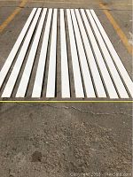 12 pieces of flat baseboard laid out on ground, each about 10 feet long