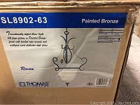 Photo of box labeling showing Thomas Lighting Raven SL8902-63 painted bronze three-light ceiling fixture details and design.