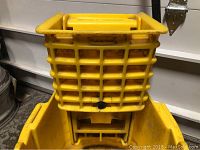 Close-up of the Rubbermaid yellow mop bucket wringer attachment showing the grid-style wringer basket with Rubbermaid label.